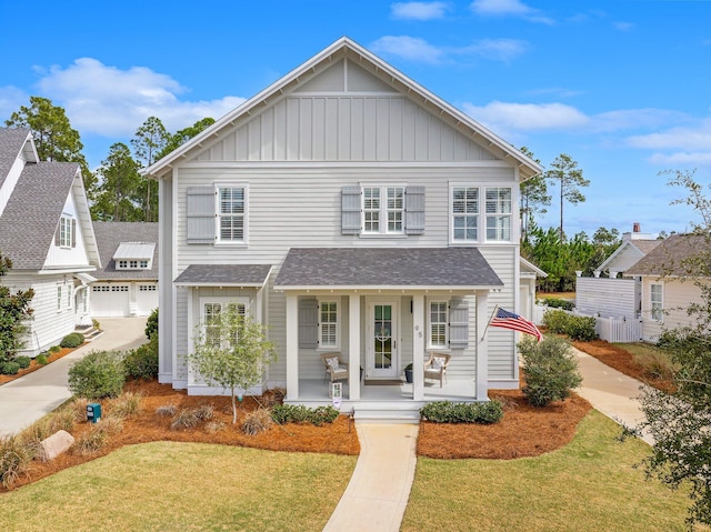 view of front of house with a porch, board and batten siding, a shingled roof, and a front lawn