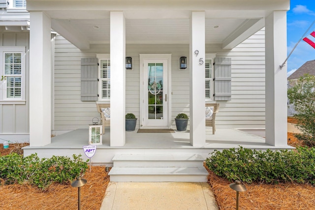 view of exterior entry with a porch and board and batten siding