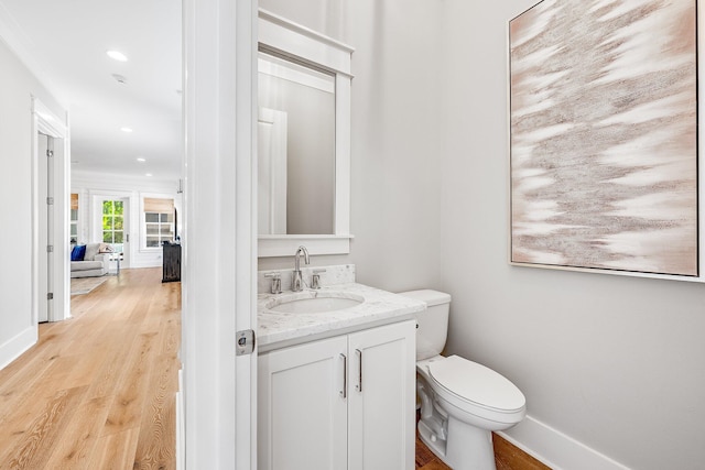 half bath featuring recessed lighting, toilet, vanity, wood finished floors, and baseboards