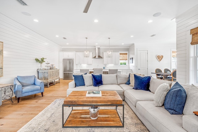 living room featuring recessed lighting, visible vents, crown molding, and light wood finished floors