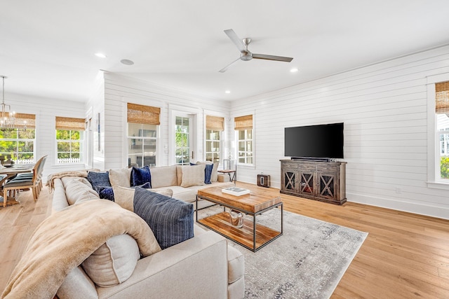 living room featuring recessed lighting, baseboards, wood finished floors, and ceiling fan with notable chandelier