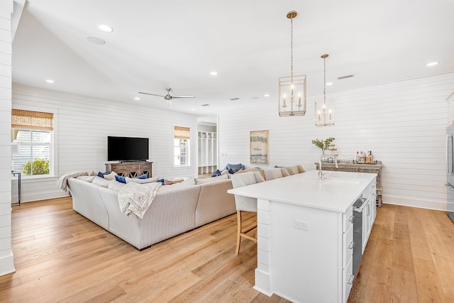 kitchen with light wood finished floors, light countertops, open floor plan, white cabinets, and a kitchen breakfast bar