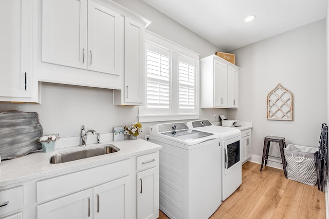 laundry area featuring washer and clothes dryer, recessed lighting, cabinet space, light wood-style flooring, and a sink