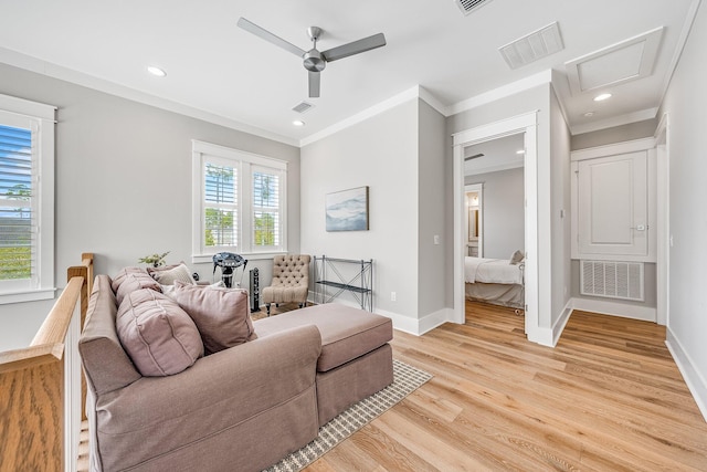 living area with ornamental molding, light wood-type flooring, and visible vents