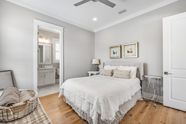 bedroom featuring recessed lighting, visible vents, light wood-style flooring, ensuite bathroom, and a sink