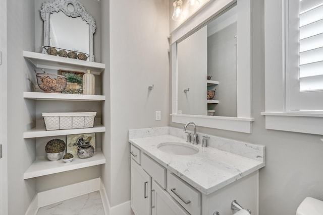 bathroom with toilet, marble finish floor, baseboards, and vanity