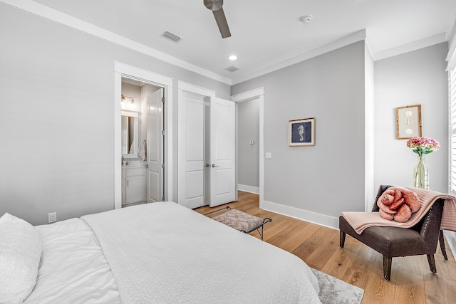 bedroom with ensuite bathroom, light wood-style flooring, visible vents, baseboards, and ornamental molding