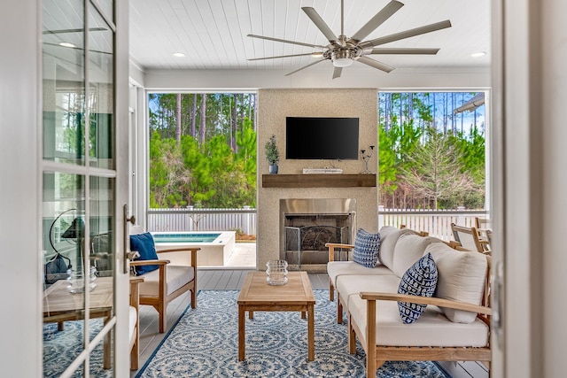 sunroom / solarium featuring ceiling fan and exterior fireplace