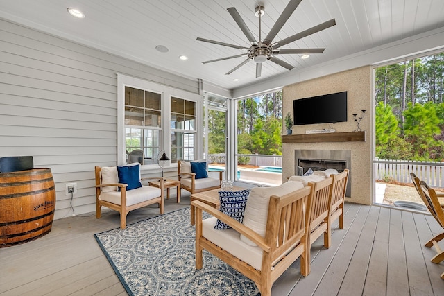 sunroom / solarium with a wealth of natural light, wooden ceiling, a fireplace, and ceiling fan