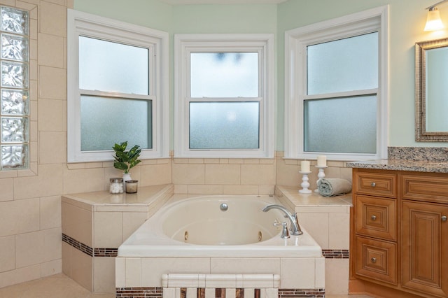 full bathroom with a healthy amount of sunlight, a jetted tub, and vanity