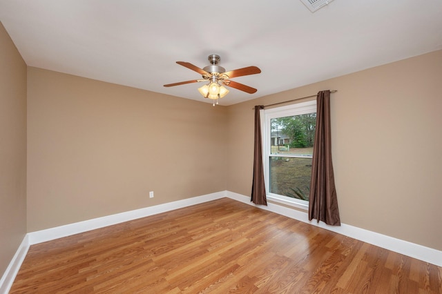 spare room featuring baseboards, a ceiling fan, and light wood-style floors