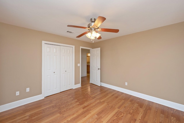 unfurnished bedroom with baseboards, light wood-style flooring, visible vents, and a closet