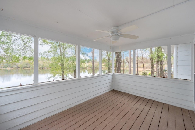 unfurnished sunroom featuring ceiling fan and a water view