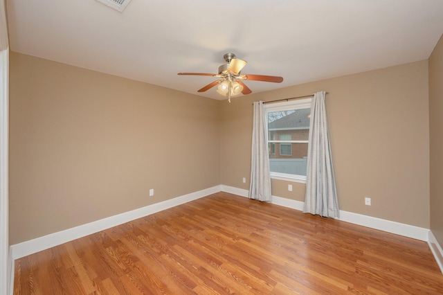 spare room with a ceiling fan, light wood-style flooring, and baseboards