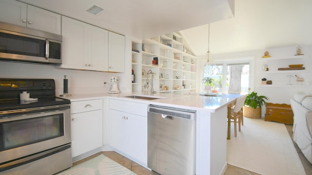 kitchen with a peninsula, white cabinets, stainless steel appliances, and light countertops