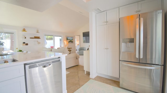 kitchen featuring light tile patterned floors, stainless steel appliances, light countertops, open floor plan, and white cabinetry