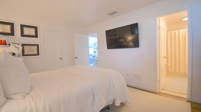 bedroom featuring baseboards, visible vents, and ensuite bath