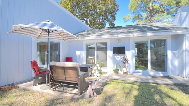 rear view of property featuring a patio area, a yard, and roof with shingles