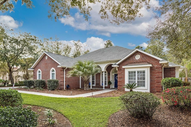 ranch-style home featuring brick siding, roof with shingles, and a front yard