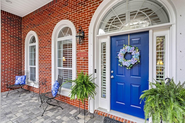 property entrance featuring brick siding and a porch