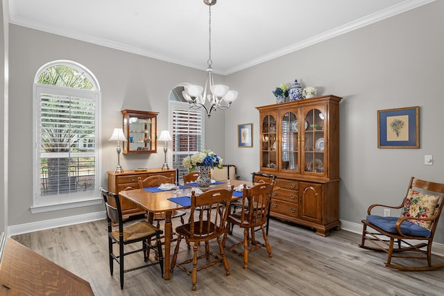 dining area with a chandelier, baseboards, light wood-style flooring, and ornamental molding