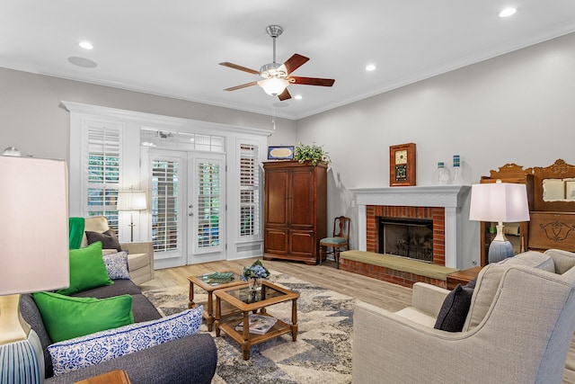 living area featuring light wood-style flooring, a fireplace, and ornamental molding