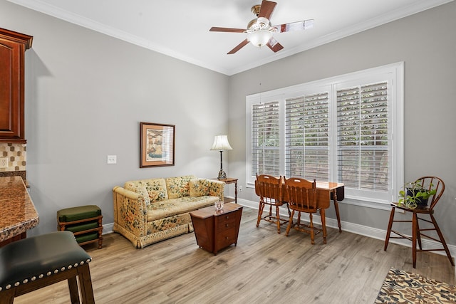 living room with light wood-style flooring, crown molding, baseboards, and ceiling fan