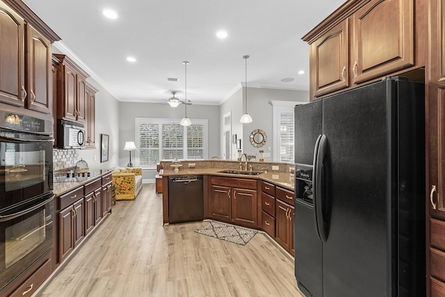 kitchen featuring light wood finished floors, a sink, black appliances, crown molding, and backsplash