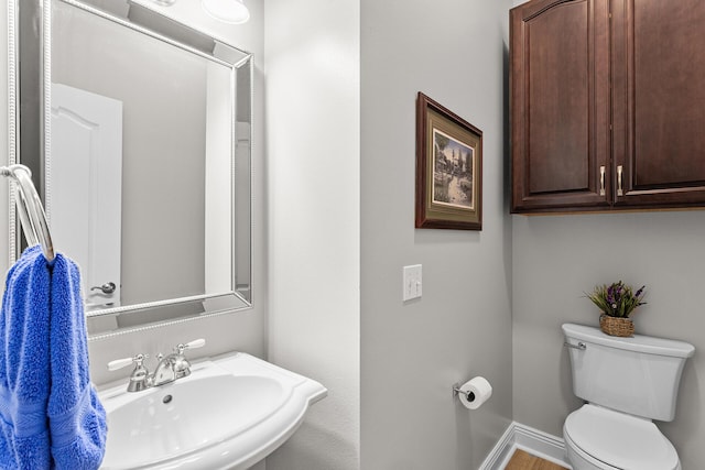 bathroom with a sink, baseboards, and toilet