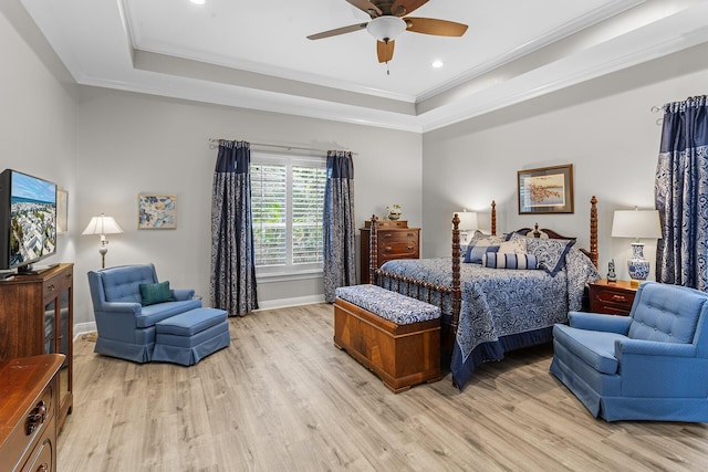 bedroom with baseboards, light wood-type flooring, a tray ceiling, and ornamental molding