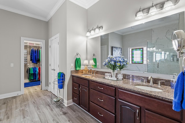 bathroom featuring double vanity, wood finished floors, crown molding, and a sink