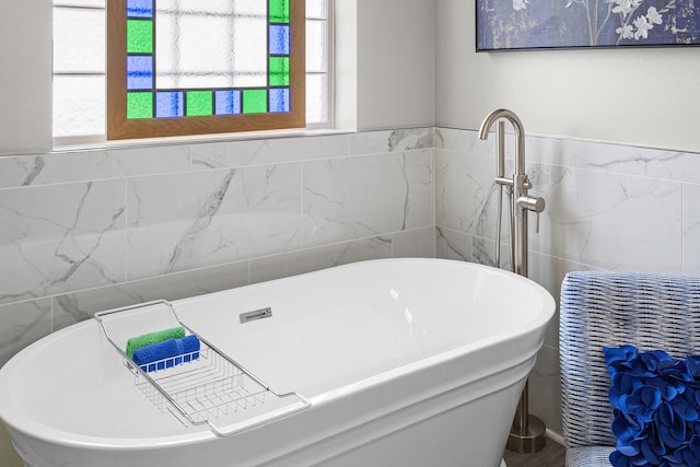 bathroom featuring tile walls and a freestanding bath