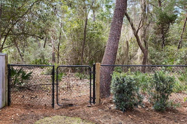 view of gate featuring a wooded view and fence