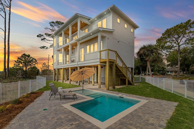 rear view of property featuring stairs, a lawn, a fenced backyard, and a balcony