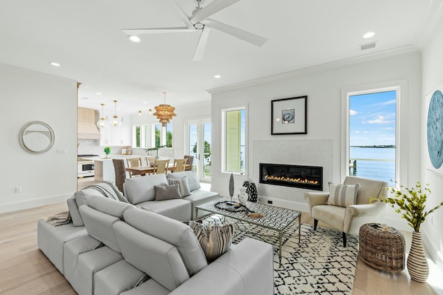 living room featuring light wood-type flooring, ornamental molding, a ceiling fan, and recessed lighting