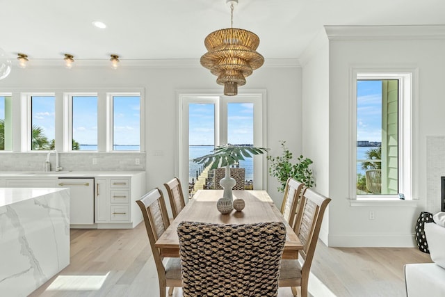 dining space featuring light wood-style floors, plenty of natural light, ornamental molding, and baseboards