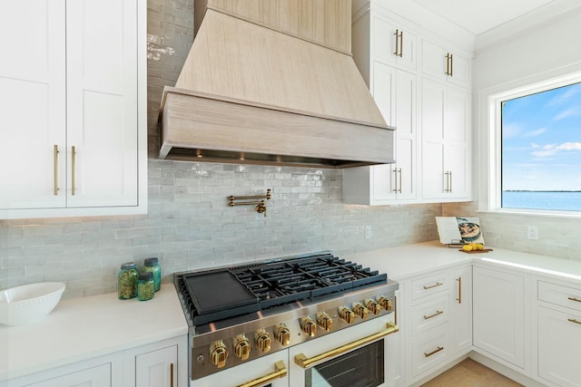 kitchen with tasteful backsplash, custom range hood, white cabinetry, and light countertops