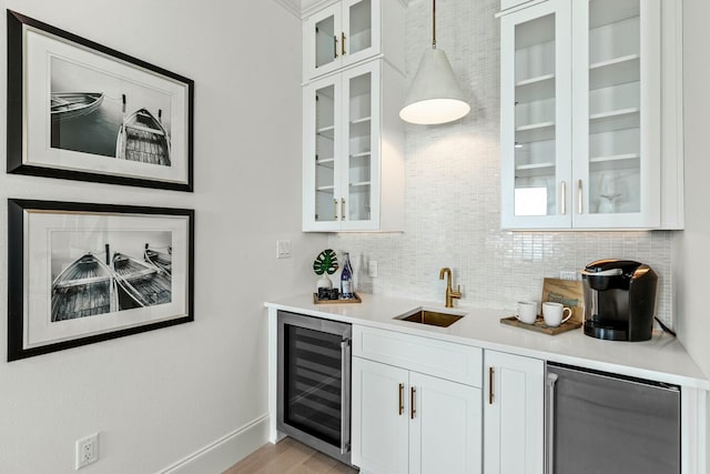 bar with indoor wet bar, decorative backsplash, a sink, beverage cooler, and fridge