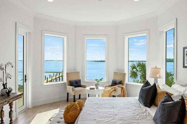 bedroom with ornamental molding, a water view, wood finished floors, and baseboards