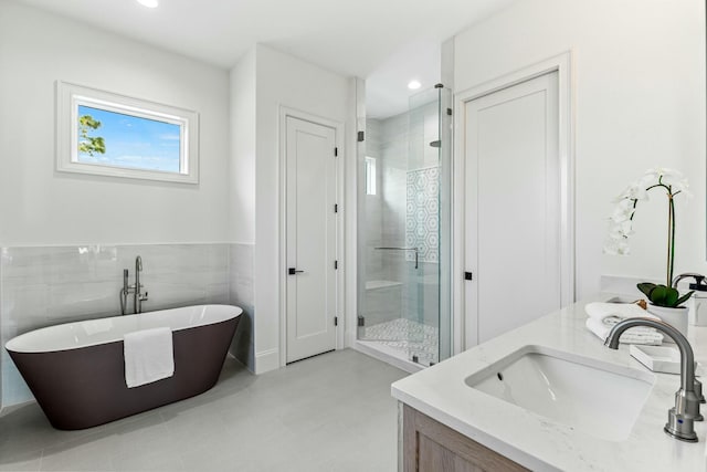 bathroom featuring a stall shower, vanity, tile walls, and a soaking tub