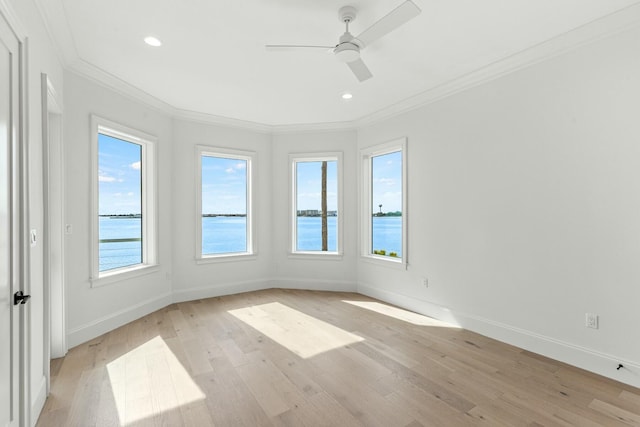 spare room featuring baseboards, light wood-style floors, a water view, and crown molding