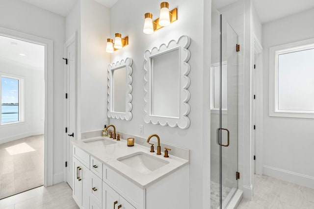 full bathroom featuring baseboards, double vanity, a sink, and a shower stall