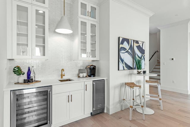 bar with wine cooler, a sink, wet bar, tasteful backsplash, and crown molding