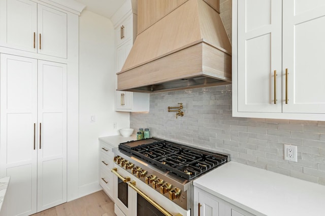 kitchen featuring custom exhaust hood, range with gas stovetop, and light countertops