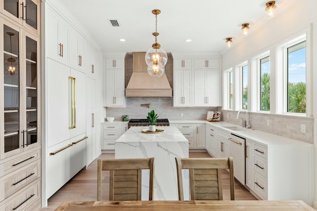 kitchen featuring stove, a kitchen island, a sink, custom exhaust hood, and dishwasher