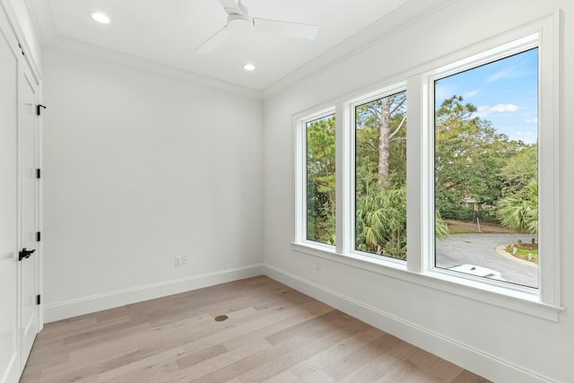 unfurnished room with light wood finished floors, plenty of natural light, ornamental molding, and baseboards