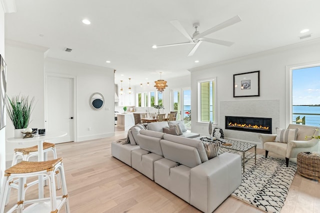 living area featuring crown molding, plenty of natural light, visible vents, and light wood-style floors