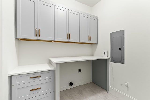 laundry area featuring cabinet space, electric panel, baseboards, light wood-style floors, and electric dryer hookup