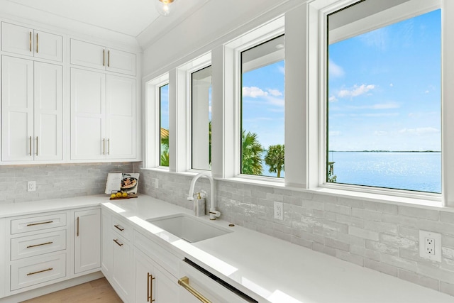 kitchen with a water view, a sink, and white cabinetry