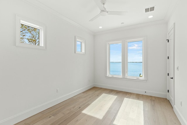 unfurnished room with ceiling fan, light wood-style flooring, visible vents, baseboards, and ornamental molding